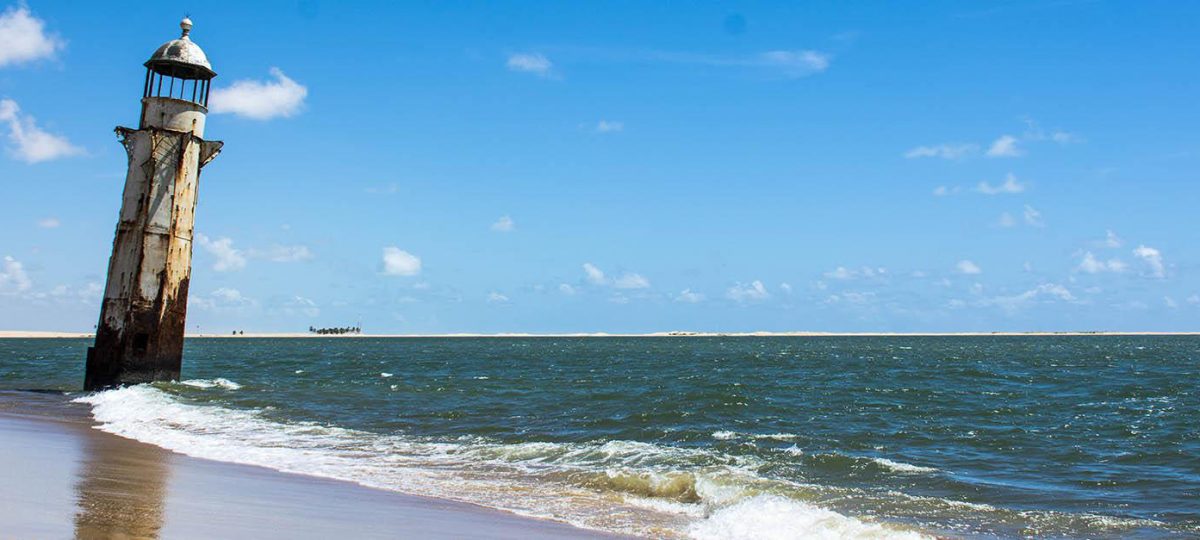 Farol histórico na Foz do Rio São Francisco, encontro do rio com o mar entre Sergipe e Alagoas, durante passeio turístico.