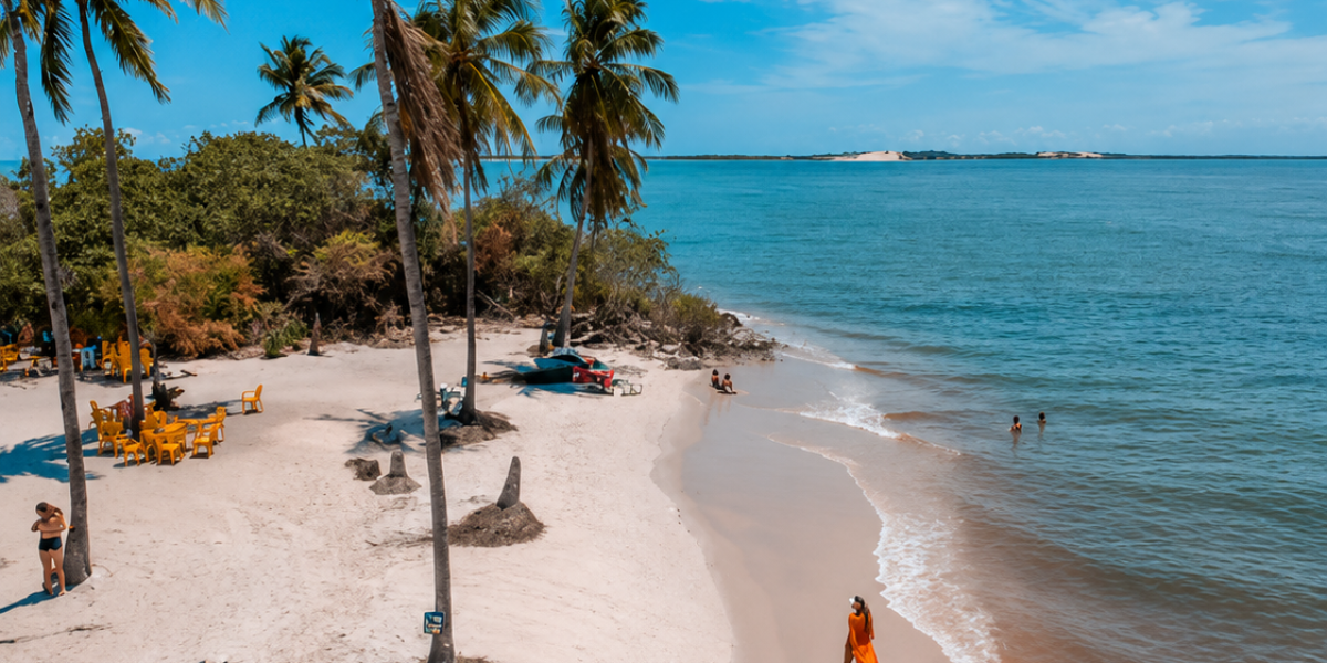 Vista panorâmica da Praia do Saco, em Sergipe, com areia branca, coqueiros, mar azul-esverdeado e paisagem paradisíaca, um dos passeios mais procurados por turistas que visitam Aracaju.